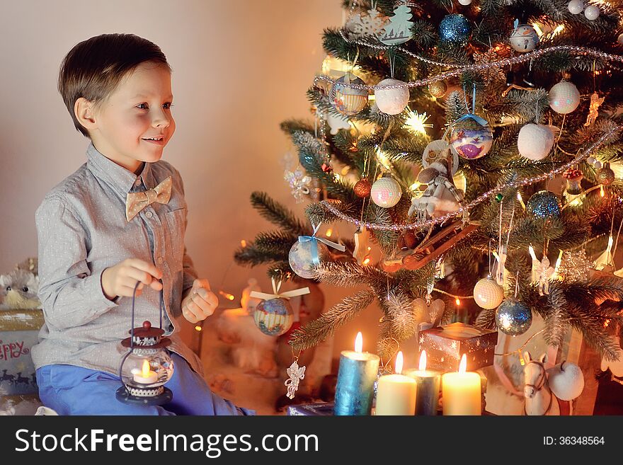 In the snow with lights garlands at home boy and Christmas tree