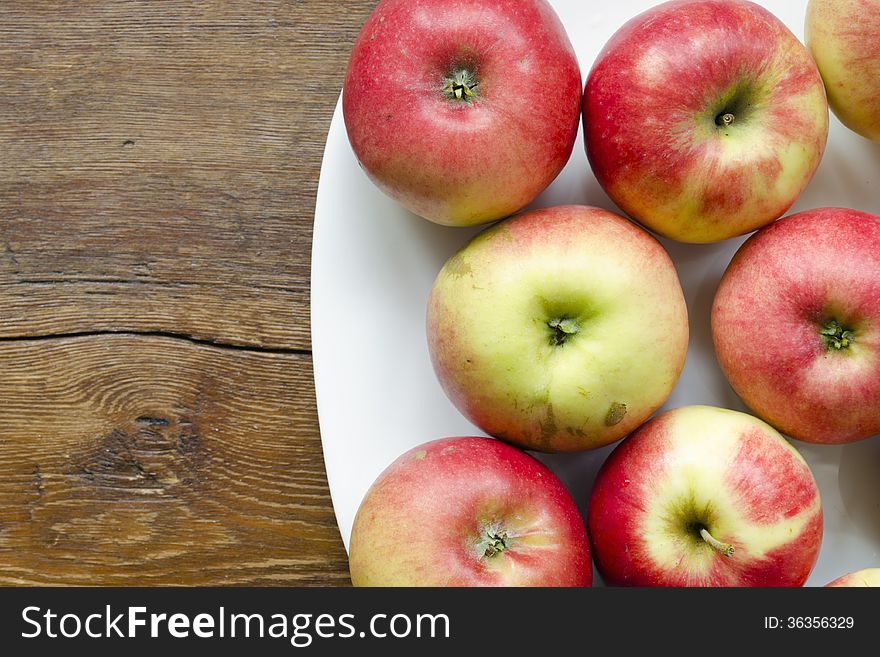 Many red apple on white plate on vintage wooden table. Many red apple on white plate on vintage wooden table