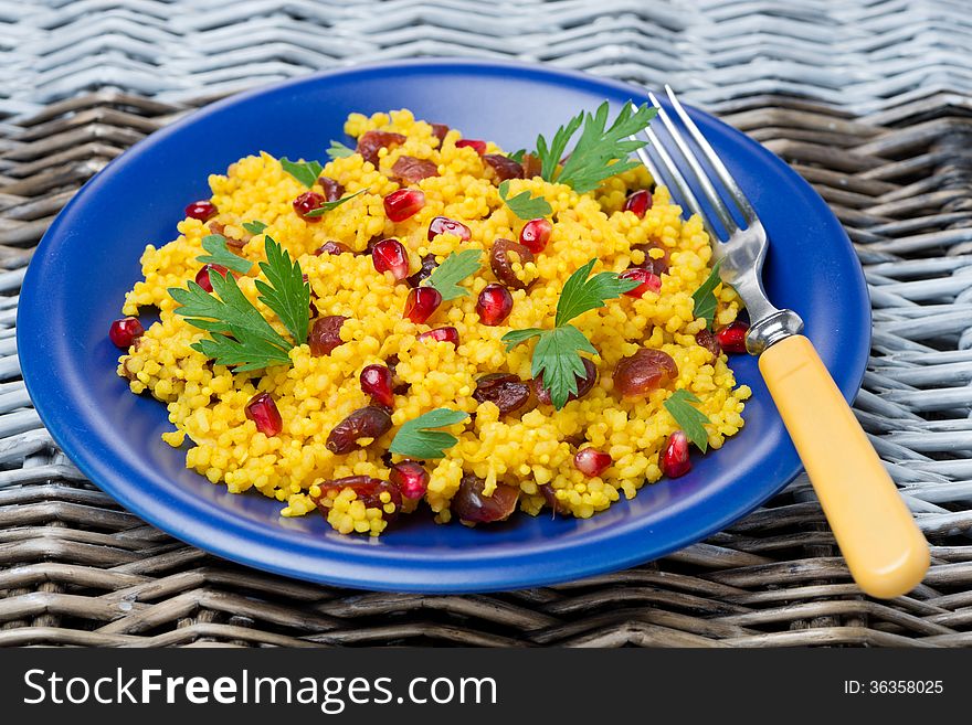 Couscous salad with curry, dried cranberries and herbs on the plate