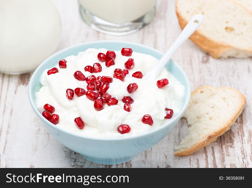 Homemade yogurt with pomegranate, milk and bread, top view, close-up