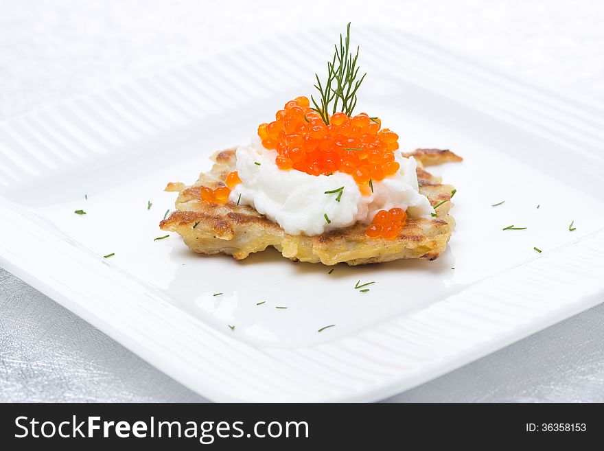 Potato pancakes with red caviar on the plate
