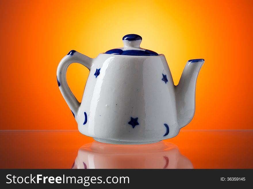 Ceramic teapot with blue stars on orange background.