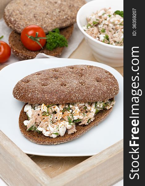 Sandwich of rye bread with tuna and homemade cheese on a tray, vertical, top view