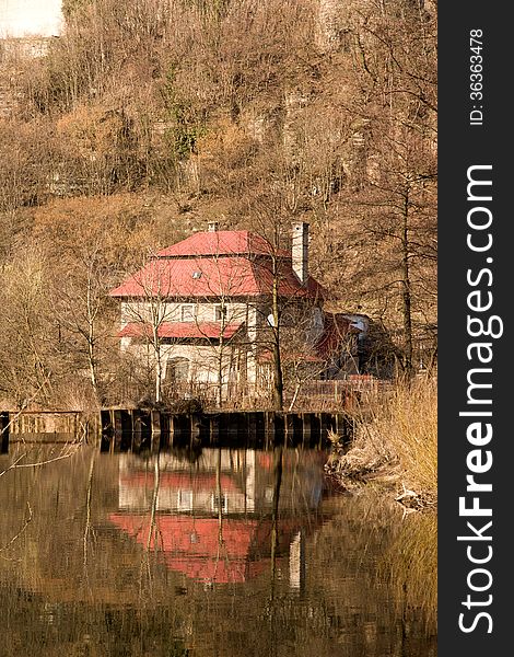 House with red roof is reflected on the surface of the river. House with red roof is reflected on the surface of the river