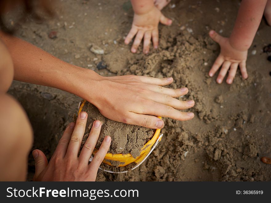 The image of hands of adult and child engaged in a game of sand. The image of hands of adult and child engaged in a game of sand
