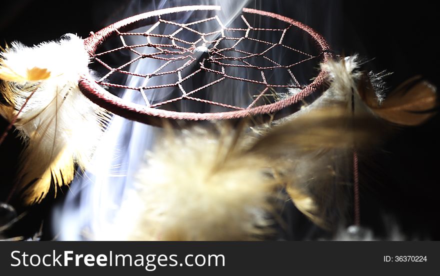 Dreamcatcher illuminated from a low angle smoke filled using an incense burner with a black background. Dreamcatcher illuminated from a low angle smoke filled using an incense burner with a black background.