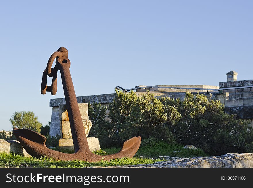 A large rusted anchor resting against some stones