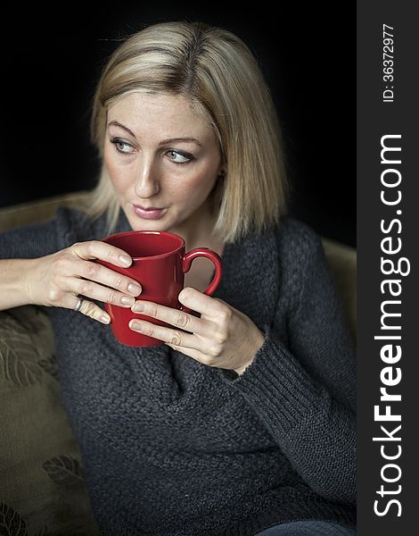 Portrait of a blonde woman with blue eyes holding a red coffee cup. Portrait of a blonde woman with blue eyes holding a red coffee cup.