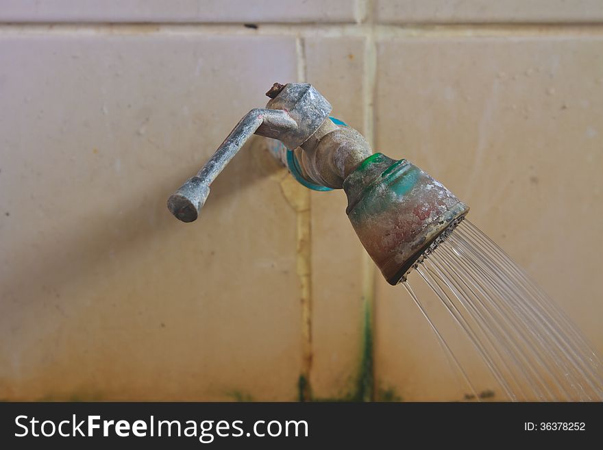 Old rusty faucet on the tile wall in bathroom