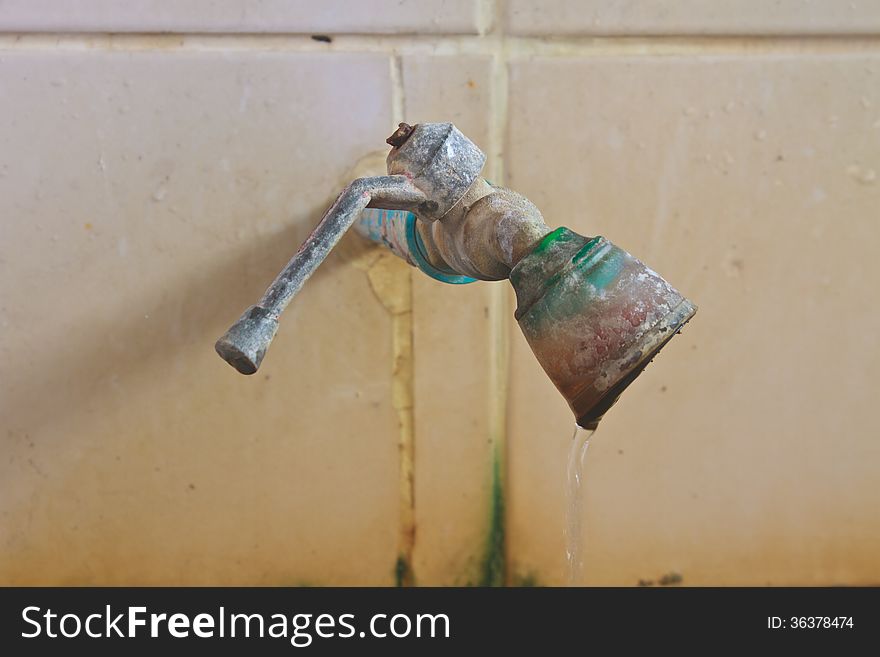 Old rusty faucet on the tile wall in bathroom