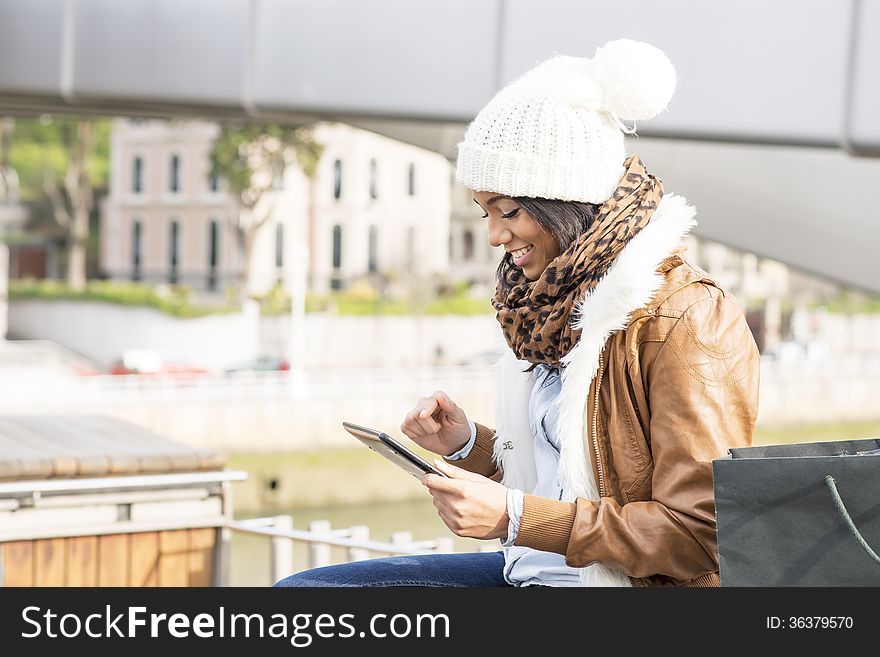 Smiling girl using tablet computer in public space. Smiling girl using tablet computer in public space.