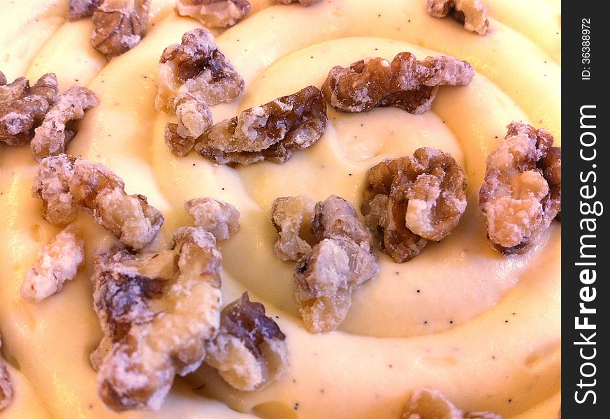A closeup of a dessert featuring candied walnuts spread on a swirl of smooth piped natural vanilla pastry cream. A closeup of a dessert featuring candied walnuts spread on a swirl of smooth piped natural vanilla pastry cream.