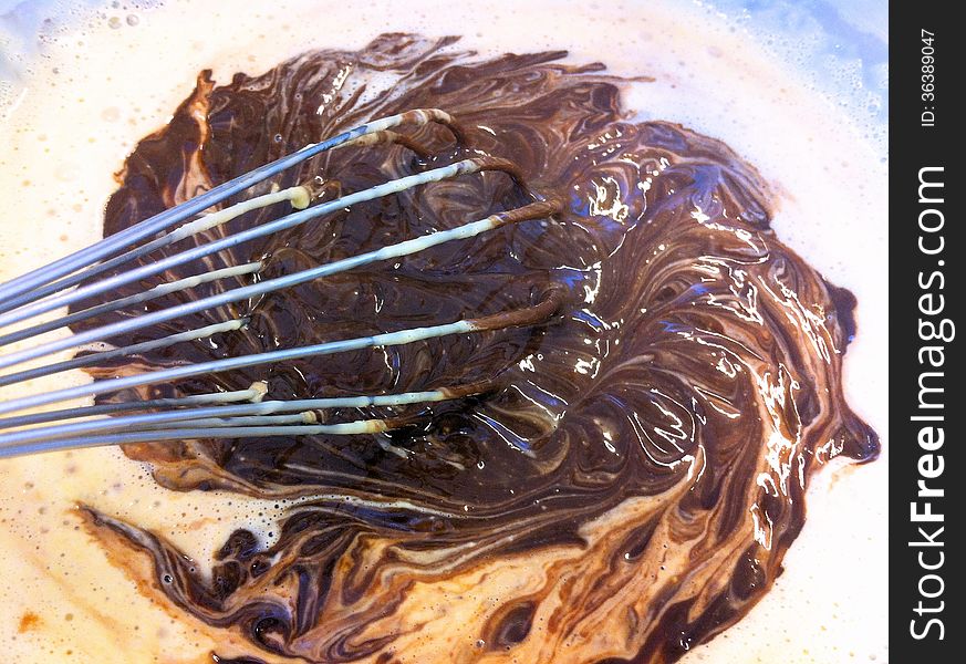 Molten chocolate mixed with hot heavy cream to create a smooth chocolate ganache with a hand whisk. Molten chocolate mixed with hot heavy cream to create a smooth chocolate ganache with a hand whisk