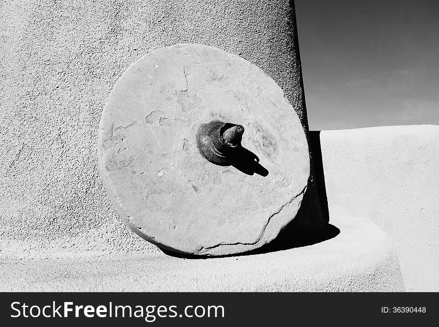 A picture of a antique grinding stone sitting on a mantel on a patio.