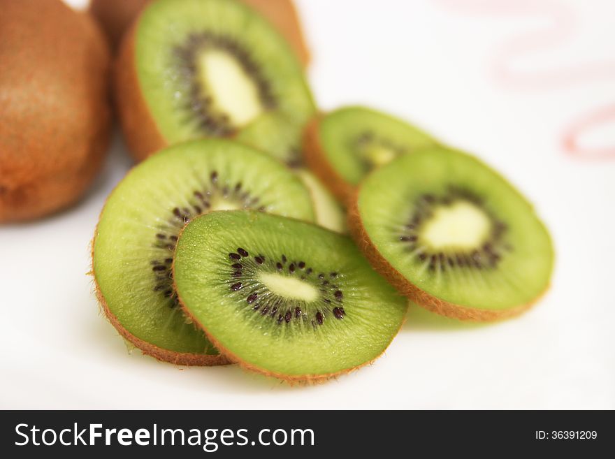 Whole kiwi fruit and it's sliced segments isolated on white background