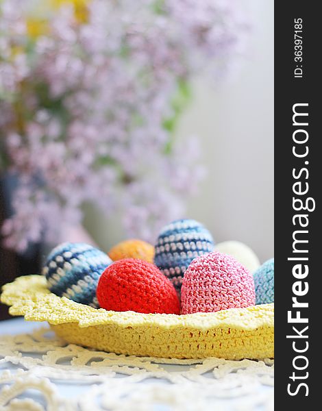 Basket of handmade knitted Easter eggs and lilac flower