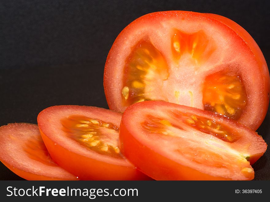 Pieces and slices of Tomato with black background.