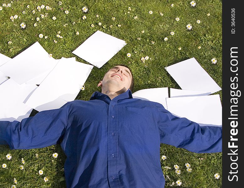 Businessman laying on the grass within his papers, happy and relaxed. Businessman laying on the grass within his papers, happy and relaxed.