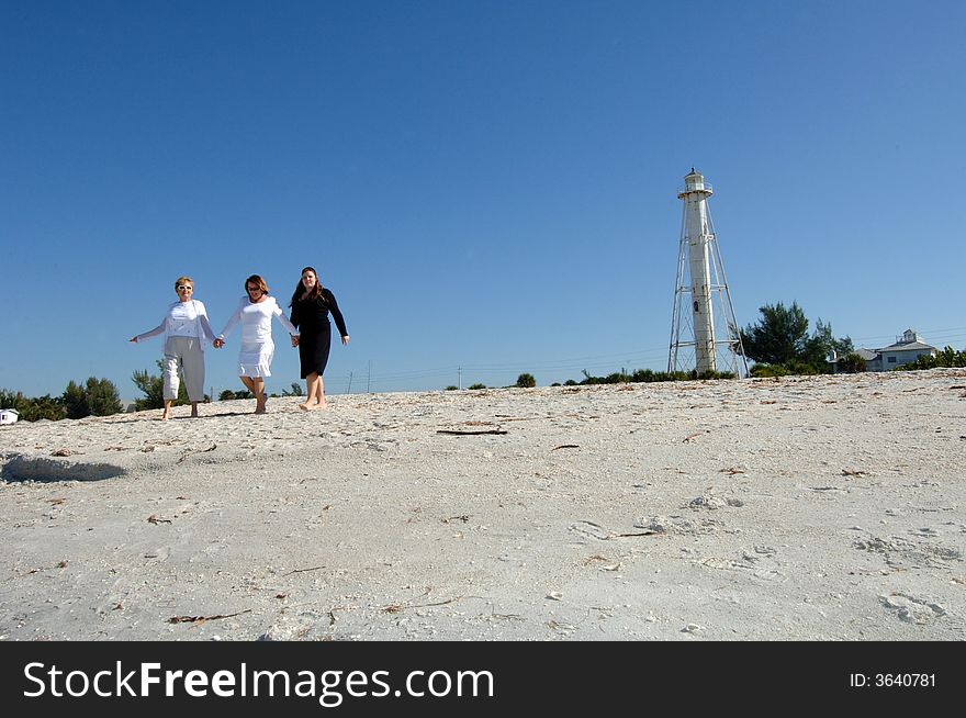 Three women of different generations walking along beach near lighthouse in Boca Grande Florida. Three women of different generations walking along beach near lighthouse in Boca Grande Florida