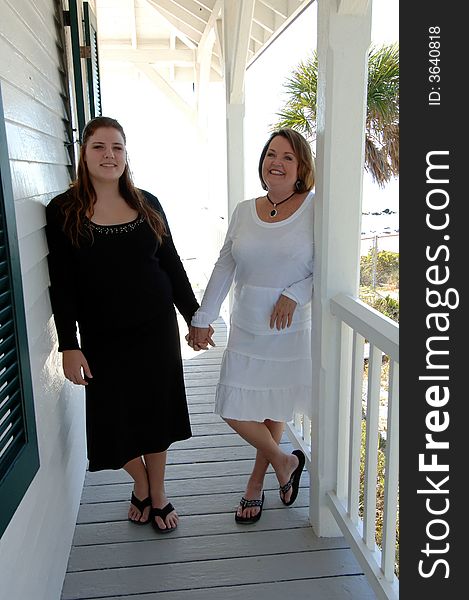 Two women of different generations holding hands standing on the porch of a beach house. Two women of different generations holding hands standing on the porch of a beach house