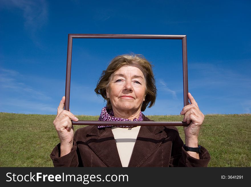 Mature and cheerful, joyful and happy woman enjoying life on a meadow - with a frame, where you can place your advertisement. Mature and cheerful, joyful and happy woman enjoying life on a meadow - with a frame, where you can place your advertisement.