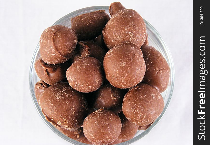 A close-up of chocolate covered peanuts against a white background. A close-up of chocolate covered peanuts against a white background.