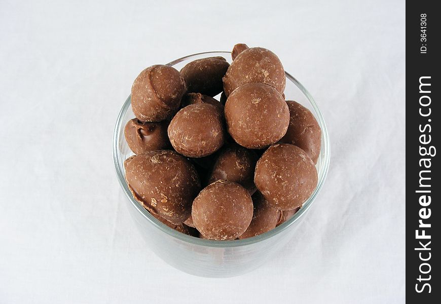 A close-up of chocolate covered peanuts against a white background. A close-up of chocolate covered peanuts against a white background.