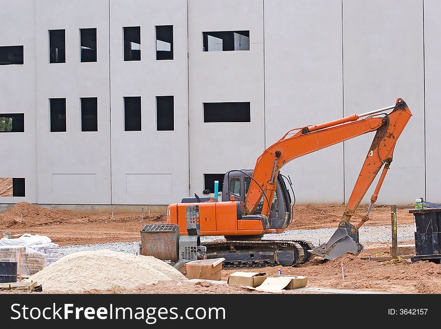 An orange front end loader at construction site with sand pile. An orange front end loader at construction site with sand pile