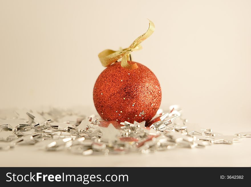 A red newyear ball laying on a silver stars garland