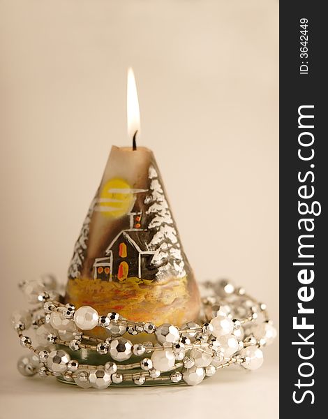 Burning candle with a silver christmas garland around it. Burning candle with a silver christmas garland around it