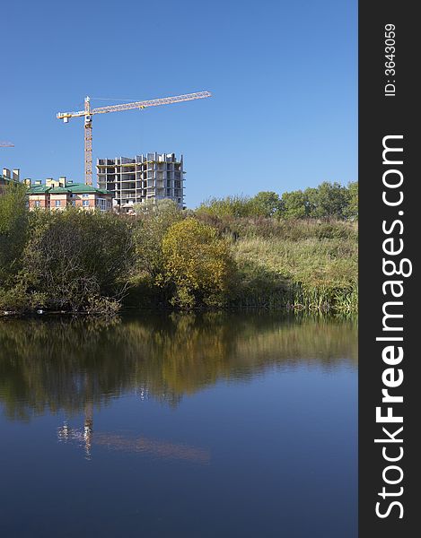 The tower crane and construction reflected in a pond. The tower crane and construction reflected in a pond