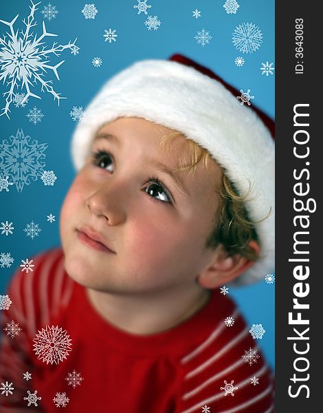 Young boy in a santa hat looking at snowflakes in the sky