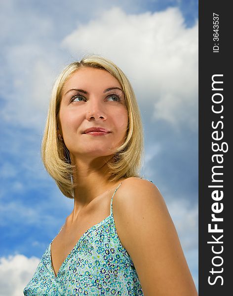 Beautiful blond girl and blue cloudy sky behind her