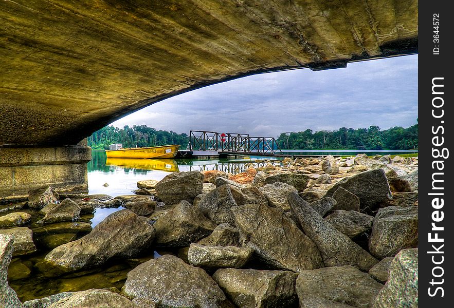 Boat moored to a jetty framed by the arching lines of the underside of a pier. Boat moored to a jetty framed by the arching lines of the underside of a pier