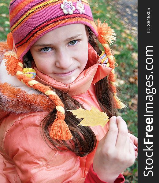 Girl holding small yellow leaf out in front of her. Girl holding small yellow leaf out in front of her