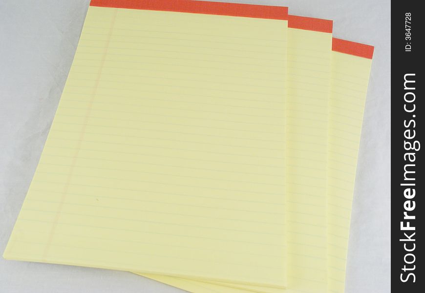 Three canary yellow lined and ruled legal pads. Three canary yellow lined and ruled legal pads.