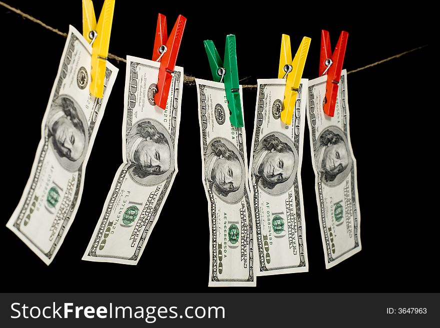100 dollar banknotes clamp attached colored linen cupboard on the ropes. The black background. Isolated black. 100 dollar banknotes clamp attached colored linen cupboard on the ropes. The black background. Isolated black.