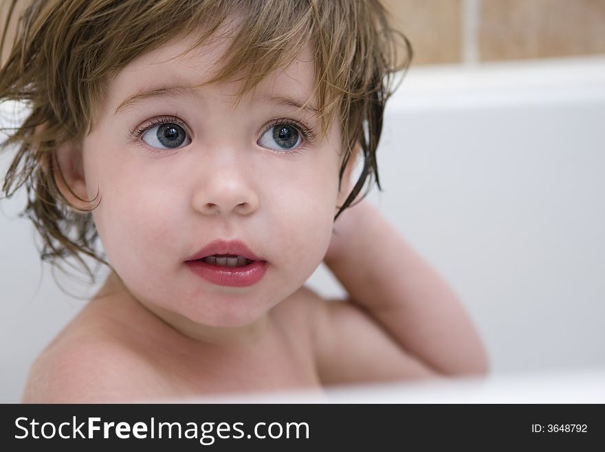 Cute little girl with messy hair sitting in a bath tub. Close up portrait with focus on the eyes. Cute little girl with messy hair sitting in a bath tub. Close up portrait with focus on the eyes.