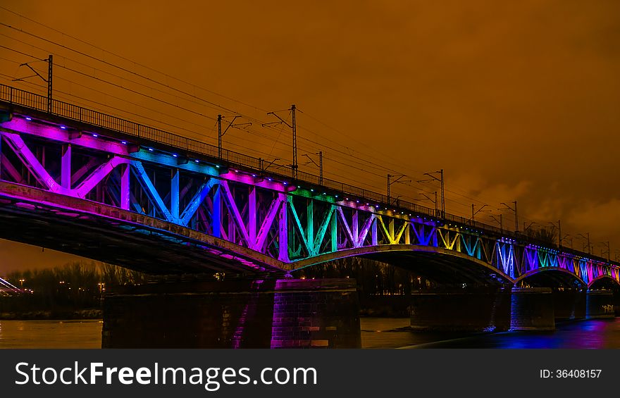 Colorfully illuminated railway bridge over Vistula river in Warsaw, Poland.
