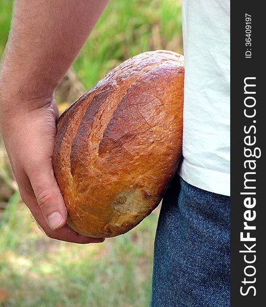 A man holds in his hands a loaf of bread. A man holds in his hands a loaf of bread.