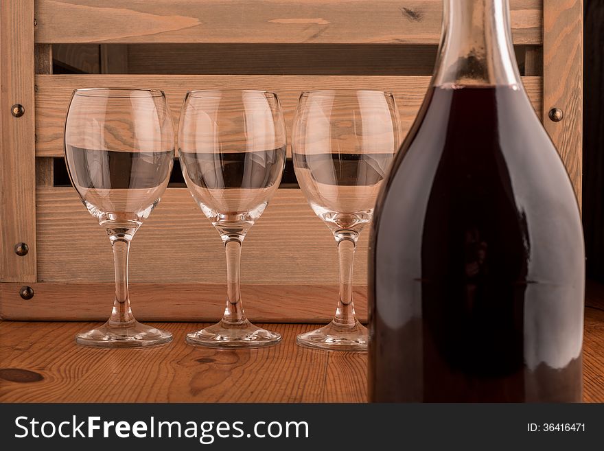 Bottle of red wine and three empty glasses on a wooden backgroung. Bottle of red wine and three empty glasses on a wooden backgroung
