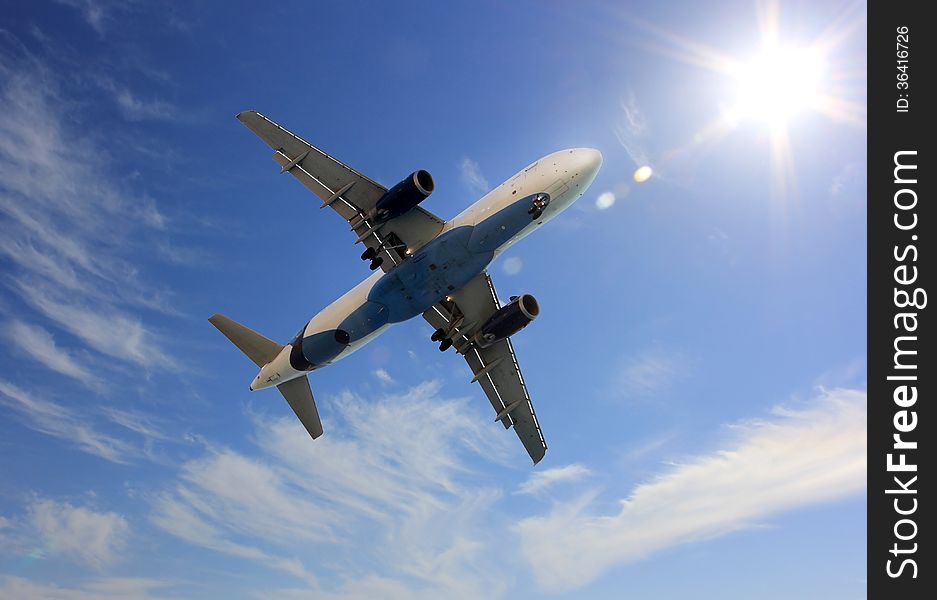 Flying airplane on a background of blue sky and bright sun. Flying airplane on a background of blue sky and bright sun