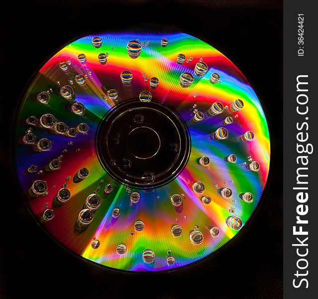 Closeup of water drops on a multicolored surface of CD. Closeup of water drops on a multicolored surface of CD