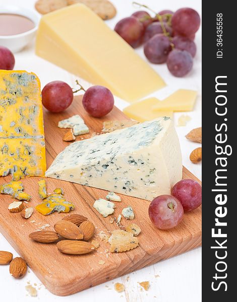 Assorted cheeses, grapes and nuts on a wooden board, close-up