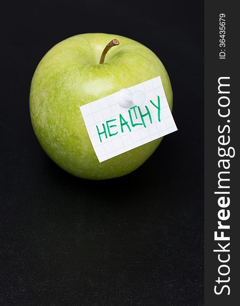 Green apple with label on a dark background, close-up