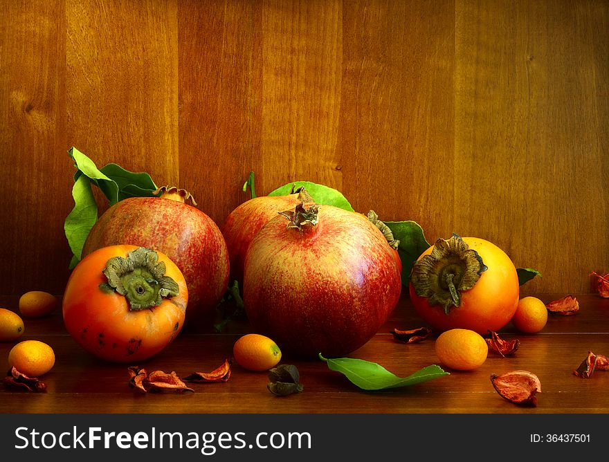 Persimmon, pomegranate and citrus on textural background. Persimmon, pomegranate and citrus on textural background