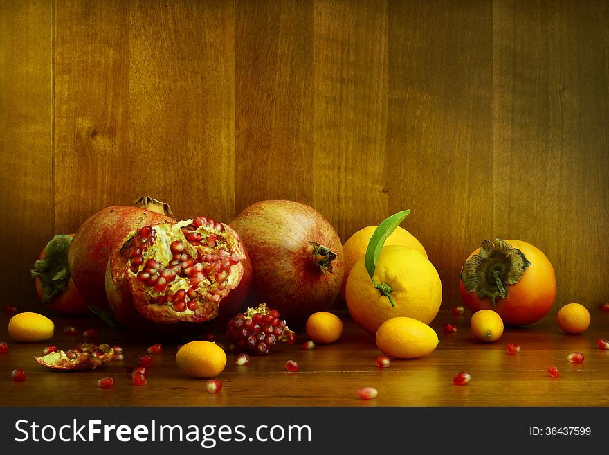 Persimmon, pomegranate and citrus on textural background. Persimmon, pomegranate and citrus on textural background