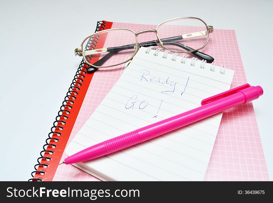 Pink pen notebook and glasses word ready