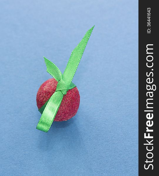 Red shoko praline with green ribbon on blue background