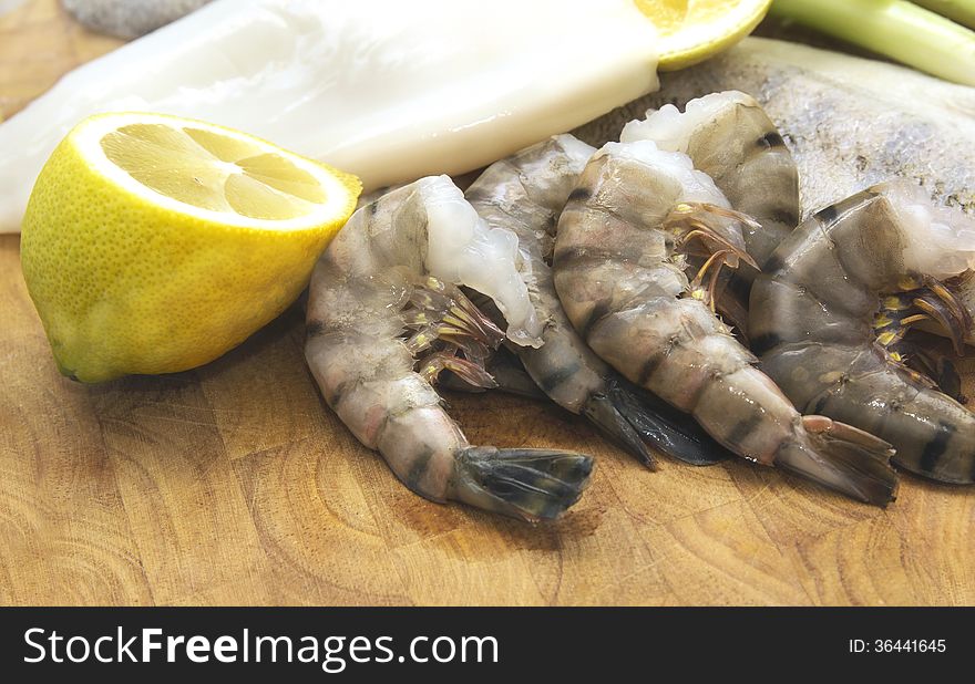 Raw seafood,cuttlefish, fish and scampi with lemon on board